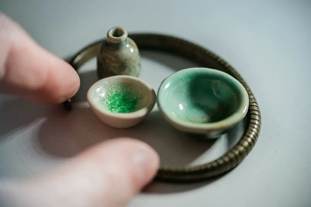 Fingers playing with miniature ceramic vase and bowls 