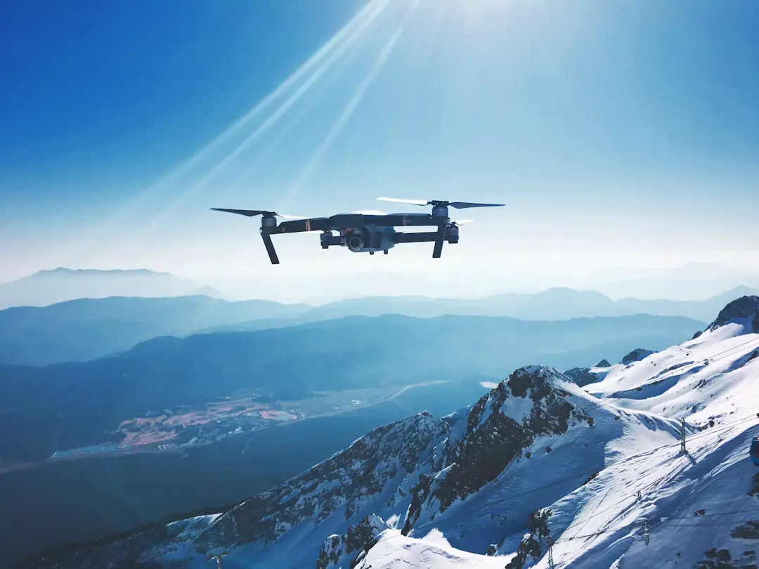 white quadcopter drone flying near snow mountain during daytime